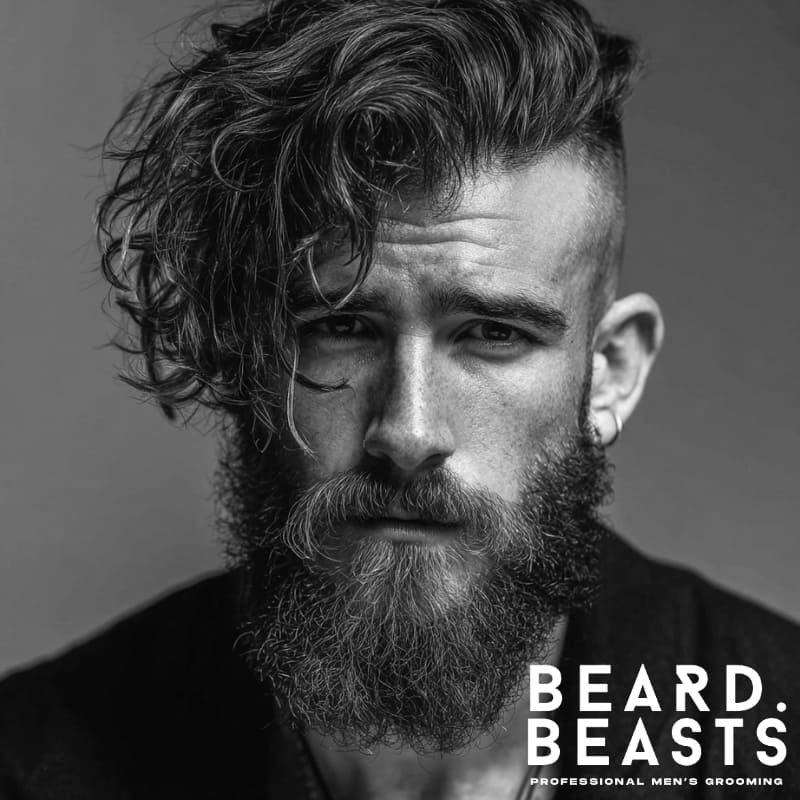 Man with wavy undercut and long beard showcasing textured volume and bold contrast.