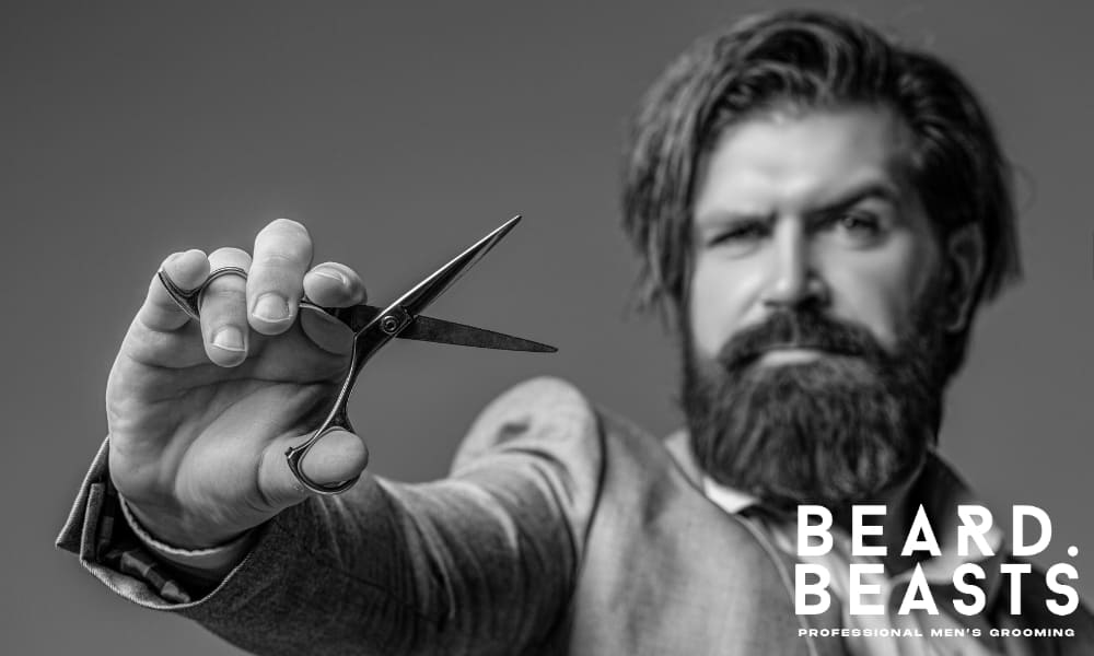 A close-up of a professional barber holding a pair of scissors, showcasing a stylish man with a beard in a barber shop setting.