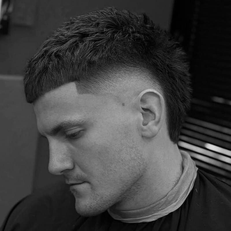 Burst skin fade textured crop hairstyle for men, featuring a sharp fade wrapping around the ear and a textured top for a bold, dynamic look.