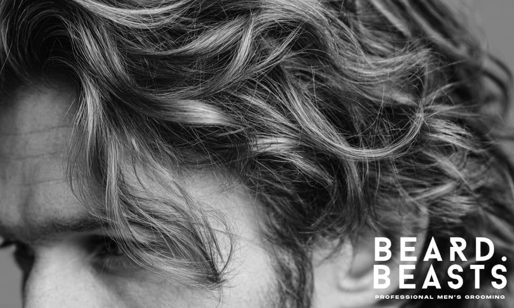 Close-up image of men's wavy hair with soft, natural waves styled with volume. The texture showcases a well-maintained wavy look, with hair flowing effortlessly and defined waves that reflect healthy and nourished hair. Ideal for demonstrating proper care for wavy hair.
