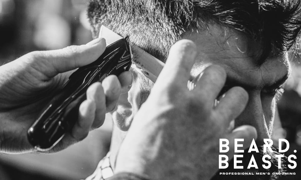 Close-up of a barber cutting a client's hair with clippers.