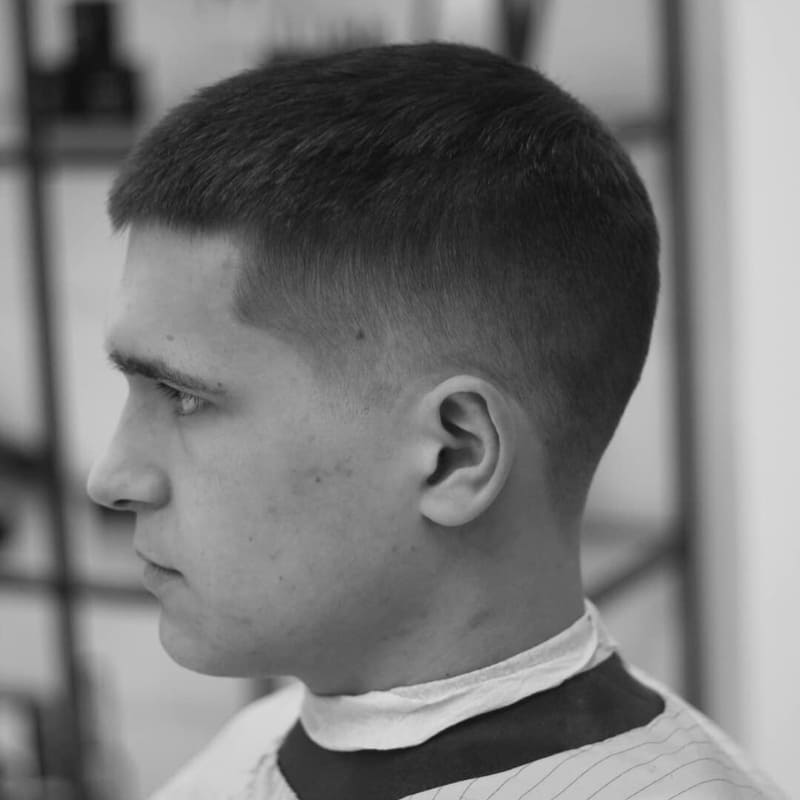 A man showcasing a crew cut taper fade hairstyle, characterized by a smooth, subtle, and gradual fade on the sides and back, creating a natural finish.