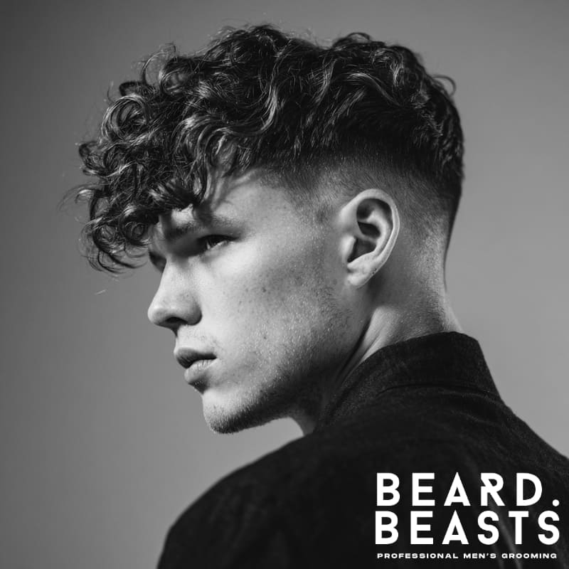 Curly long textured fringe haircut with clean fade on the sides, showcasing volume and natural curl for a bold, modern look. Beard Beasts professional grooming.
