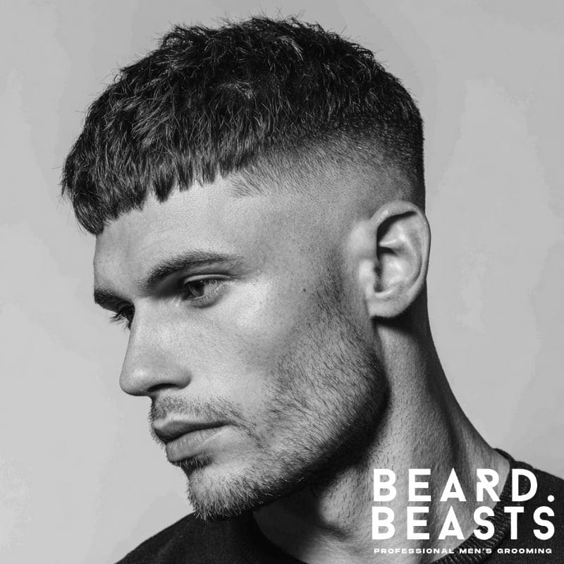Side profile of a man with a high skin fade and textured fringe haircut, showcasing a clean fade and voluminous top.
