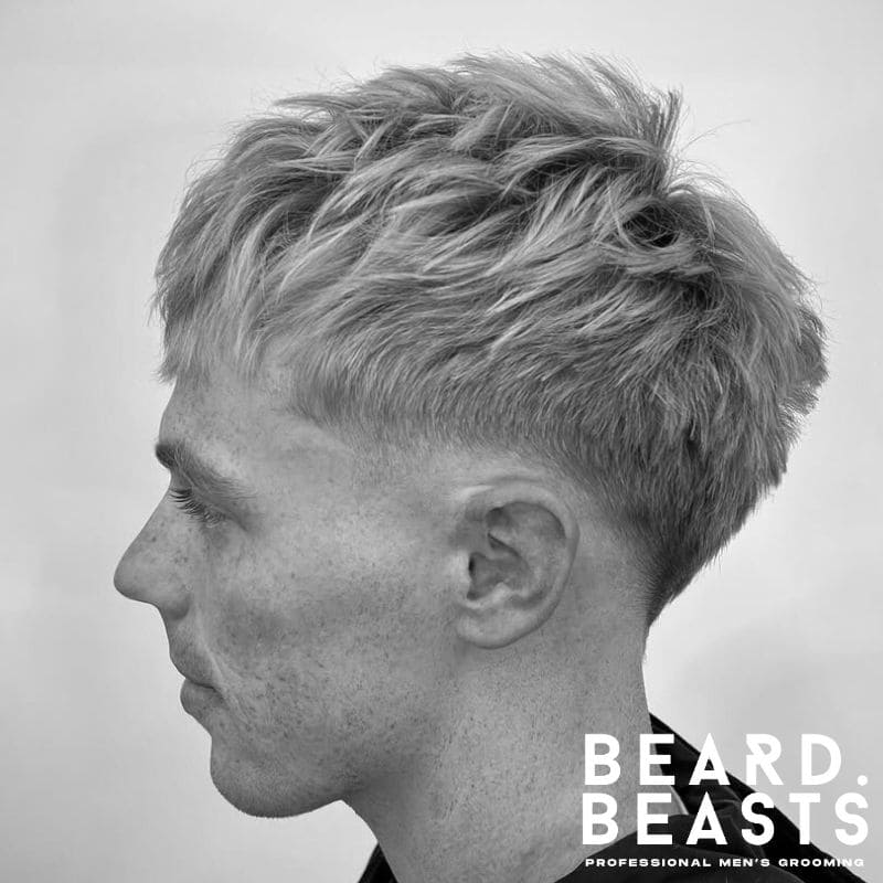 Side profile of a man with a low skin fade and textured fringe haircut, showcasing natural volume and a clean fade.