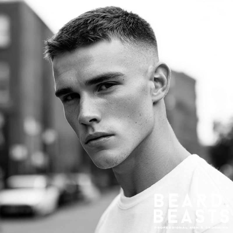 A man sporting a modern crew cut hairstyle, featuring a sharp skin fade on the sides and thicker, textured hair styled on top.