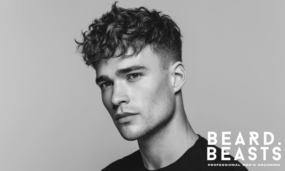 Professional young male model with a well-groomed hairstyle, featuring soft, defined waves on top and short sides. The hairstyle offers a polished, modern look with a natural, textured finish, perfect for showcasing a clean and sharp appearance.