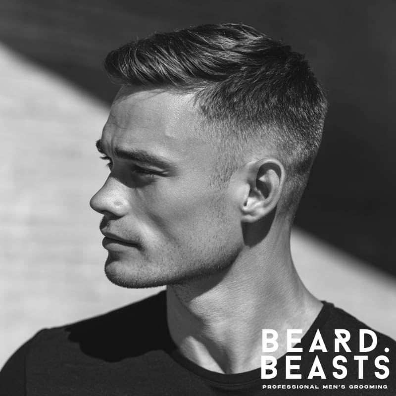 A man showcasing a side swept crew cut fade hairstyle, featuring a longer top elegantly swept to one side with a smooth fade on the sides.