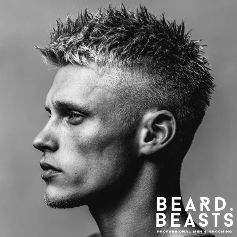 A man showcasing a spiky crew cut hairstyle, featuring bold, intentionally spiked hair on top that dramatically contrasts with short, faded sides.