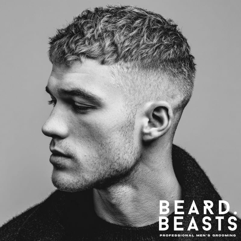 A man showcasing a textured crew cut hairstyle, featuring dynamic volume and distinct dimension on top with neatly faded sides.