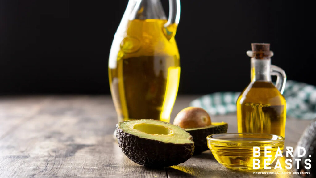 Glass bottles of avocado oil with fresh ripe avocado on a wooden table, a nutrient-rich carrier oil for dry and coarse beards.