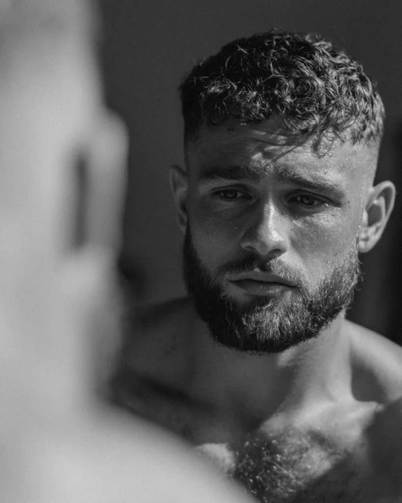 Bearded man checking how his haircut and beard work together in the mirror