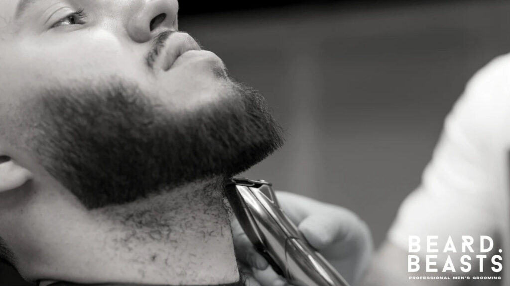 Barber using a trimmer to define the neckline of a man’s beard for a sharp and structured look