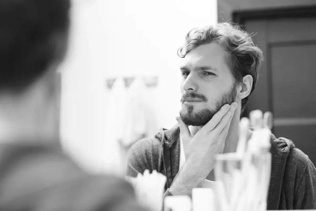 Man checking beard shape in the mirror before trimming his beard