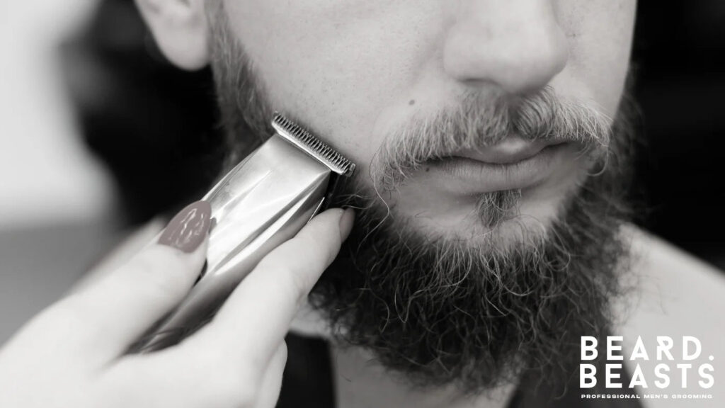 Barber shaping the cheek line of a man’s beard with a trimmer for a clean and defined look