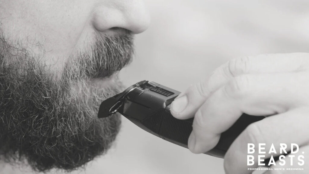 Man trimming his beard with an electric trimmer and guard to reduce bulk evenly and maintain shape
