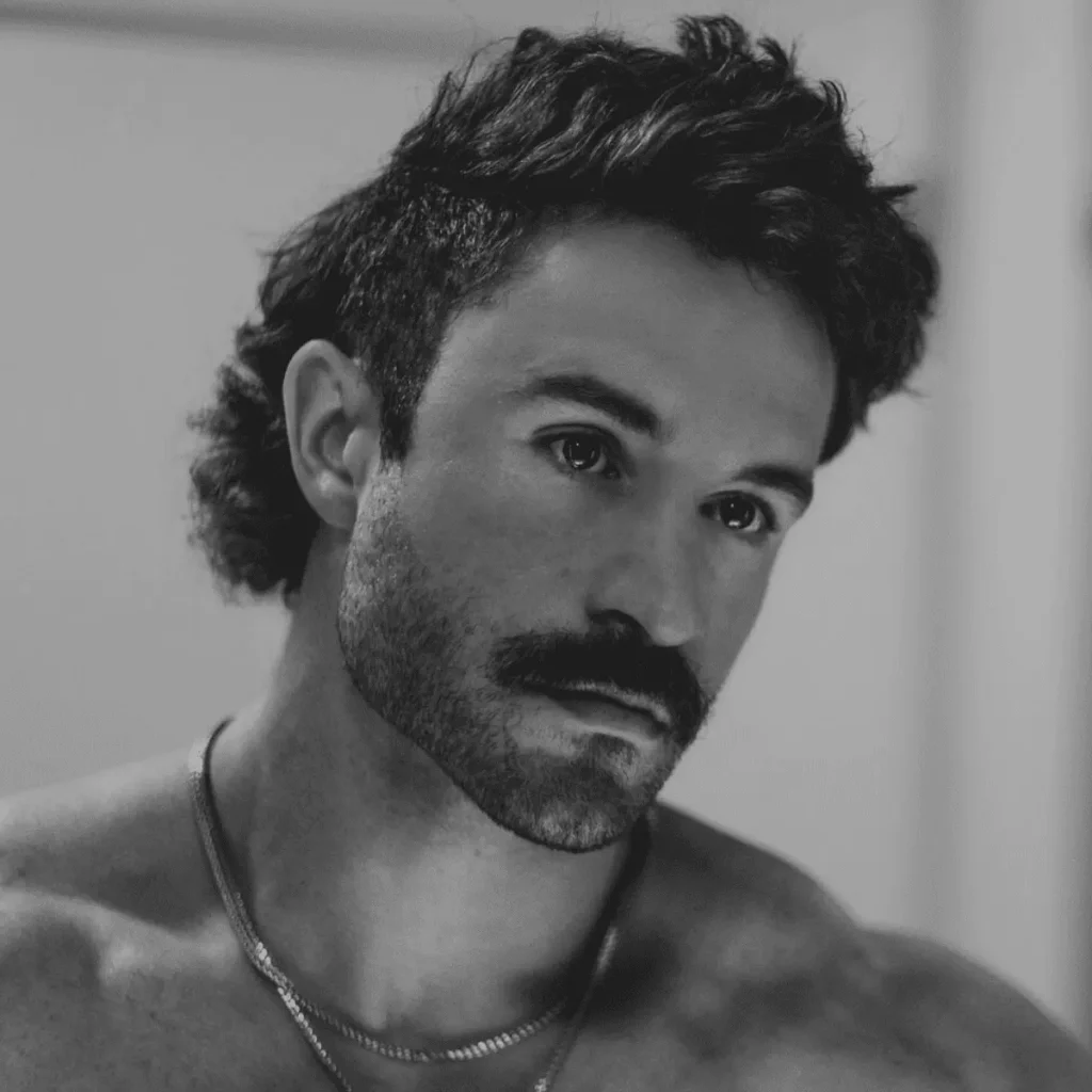 Man sporting a beardstache with heavy mustache and short scruff, showing how the style adds horizontal balance and strengthens a heart-shaped face.