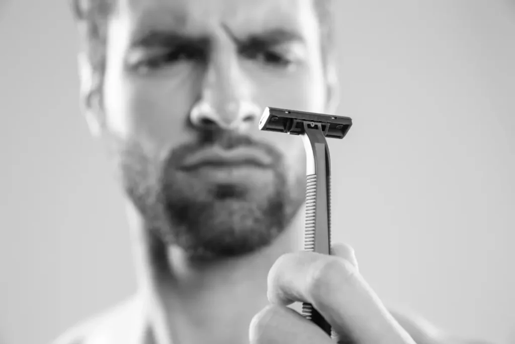 Bearded man holding a razor to show the shaving-free benefits of having a beard
