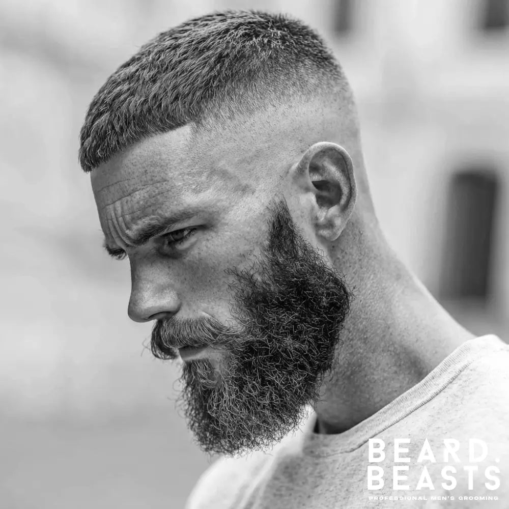Side profile of a man with a full thick beard and sharp drop fade haircut, a modern grooming look that suits a heart-shaped face