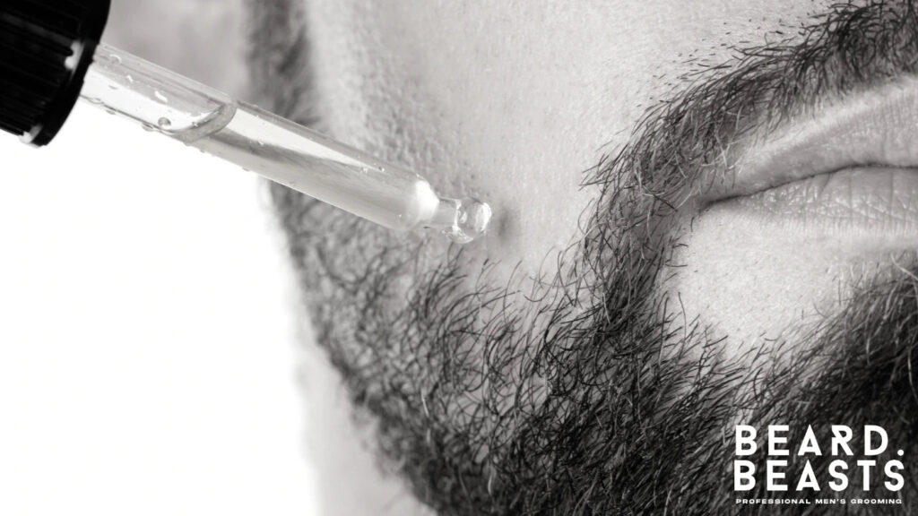 Close-up of a man applying beard oil with a dropper, illustrating the step-by-step grooming strategy to soften coarse, rough beard hair.