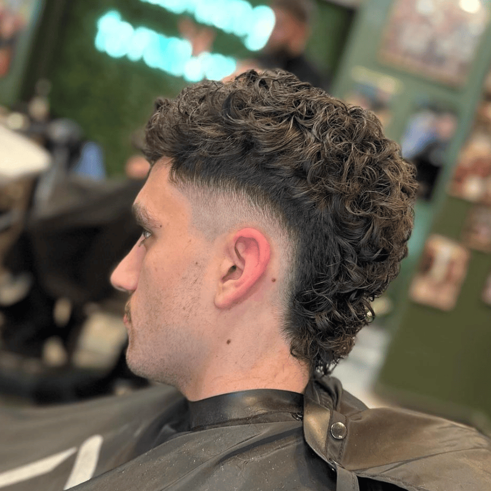 Curly Mohawk Fade showcasing natural, voluminous curls on top with a smooth taper fade on the sides and back.