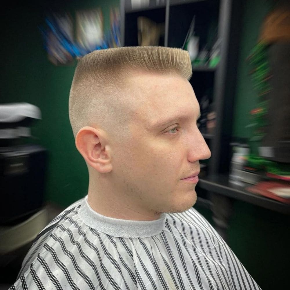 Man with a flat top hairstyle, featuring faded sides and a squared, level top, showcasing a bold and structured military haircut for men.