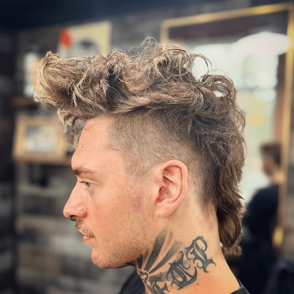 Long Mohawk Fade featuring highly textured, wavy hair on top and clean, buzzed sides.