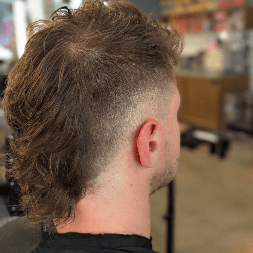 Mohawk Mullet Fade featuring faded sides transitioning into longer, textured hair at the back.