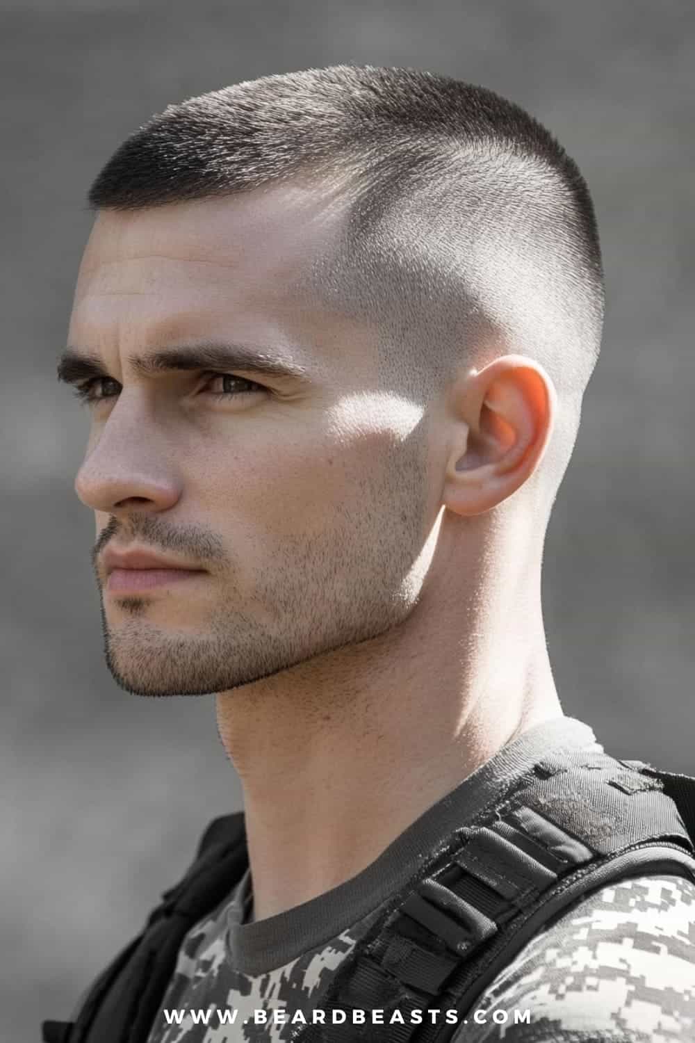 A close-up image of a man with a Recon Cut hairstyle, showcasing the military precision and sharpness typical of military haircuts for men. The haircut features very short, closely shaved sides with a slightly longer top, creating a clean and disciplined look. The man