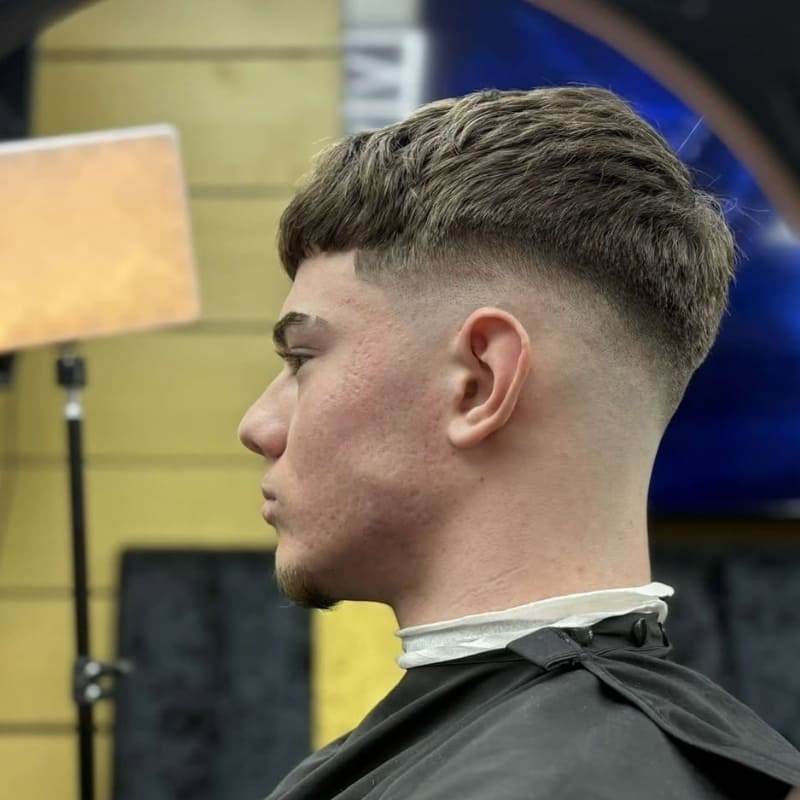 Tapered fringe French crop with drop mid fade featuring softly layered top and gradual fade around the ears – a clean and modern men's haircut ideal for enhancing jawline and cheek structure in grooming trends.