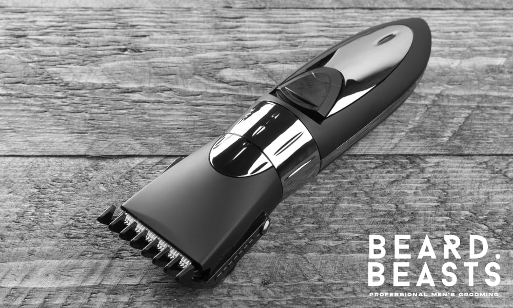 A sleek, modern electric hair clipper with a black and chrome finish, resting on a rustic wooden surface. The clipper features an adjustable guard, making it ideal for precision grooming, including short haircuts, beard trimming, and facial hair maintenance. The high-quality design reflects durability and professional-grade performance.
