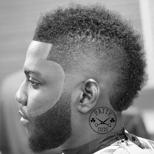 A bold Afro burst fade mohawk haircut, featuring a sharp skin fade on the sides that seamlessly transitions into a textured, voluminous top. The crisp lineup and precisely shaped beard enhance the edgy yet clean look, making this fade haircut a stylish choice for those who want a standout, modern hairstyle.