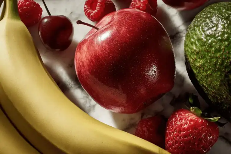 Assorted whole fruits including apple, banana, berries, and avocado used to support skin health and beard growth