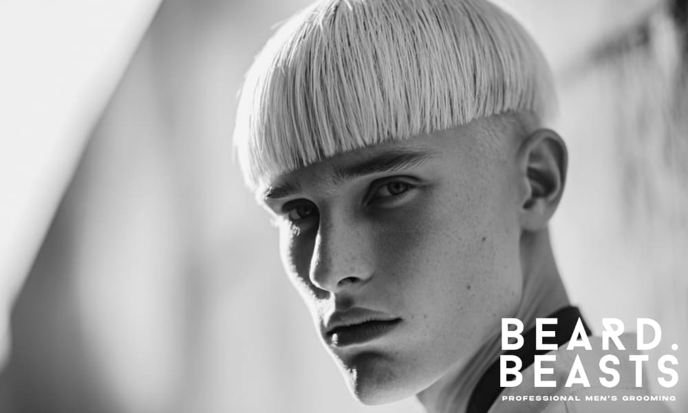 A bold blunt bob haircut for men, featuring a straight-across fringe and a clean, modern look. The sharp, defined lines create a strong, edgy appearance that contrasts with the natural features, giving a fashion-forward and contemporary vibe.