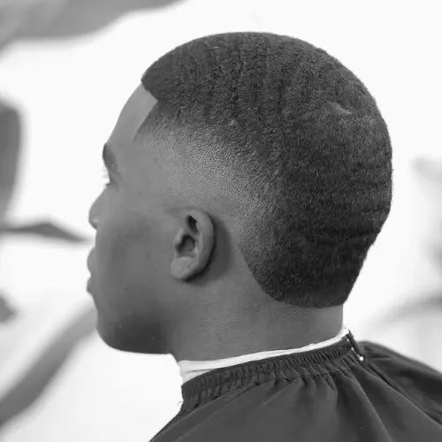 A clean and stylish burst fade haircut, featuring a smooth gradient fade that curves around the ears and blends seamlessly into the textured top. The precise lineup and subtle wave pattern add to the polished look, making this haircut a modern and versatile choice for men seeking a fresh, sharp style.