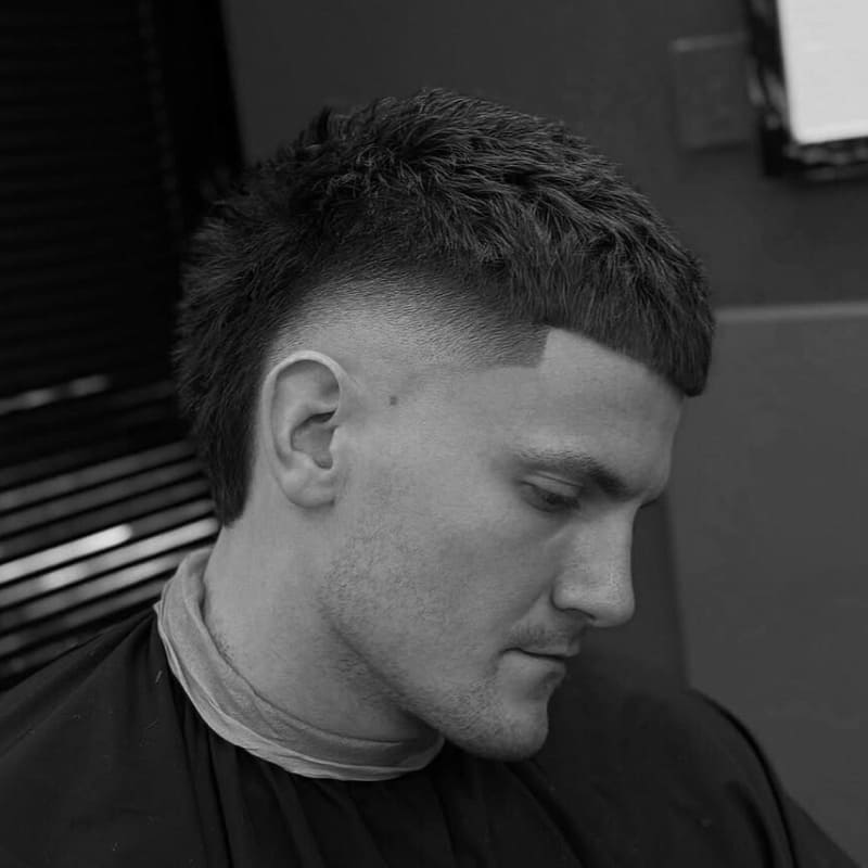 Man with a textured crop and burst fade, featuring a sharp, defined top and dramatic fade on the sides for a bold, modern style.