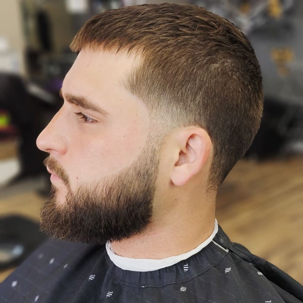 A close-up side profile of a man with a temple fade. The style has a short, even length on top with a subtle fade starting at the temples and blending smoothly into the sides and back. The temple fade is clean and precise, adding a modern touch to the classic style.