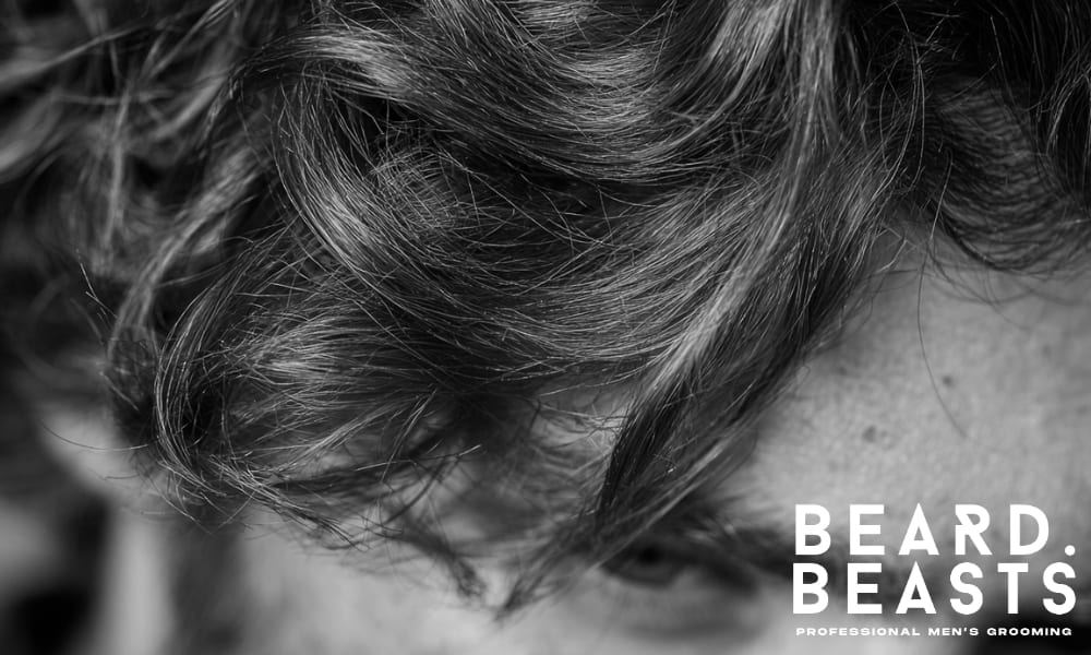 Close-up of a man’s wavy hair, showing natural texture and volume with defined waves, ideal for learning how to care for your hair.