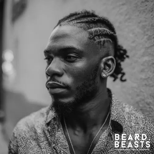 A sleek and modern cornrow fade haircut for Black men, featuring precisely braided cornrows with a sharp fade on the sides and a crisp lineup. The well-groomed beard complements the look, adding to the bold and sophisticated style. This trendy fade haircut blends cultural heritage with contemporary grooming, making it a standout choice for those who want a clean yet stylish appearance. Beard Beasts branding emphasizes professional men’s grooming.