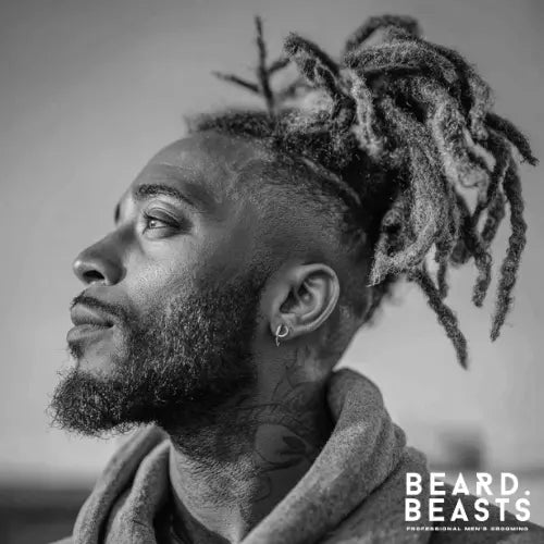 A stylish dread fade haircut for Black men, featuring thick, well-groomed dreadlocks tied back, complemented by a sharp high fade and clean lineup. The look is enhanced by a well-shaped beard, creating a modern and sophisticated style. Perfect for men seeking a bold yet refined fade haircut with dreadlocks. Beard Beasts branding in the corner emphasizes professional men's grooming.