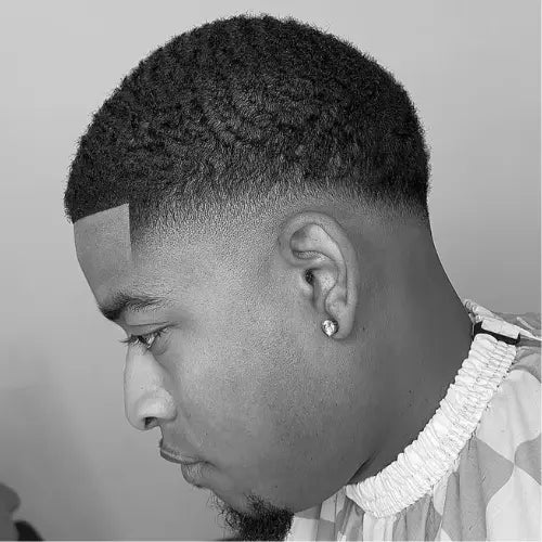 A clean and stylish drop fade haircut for Black men, featuring a smooth fade that curves naturally around the head, blending seamlessly into a textured top. The sharp lineup enhances the crisp and polished look, making this fade haircut a perfect choice for those seeking a modern, well-groomed style. The addition of a neatly shaped beard complements the overall fresh appearance.