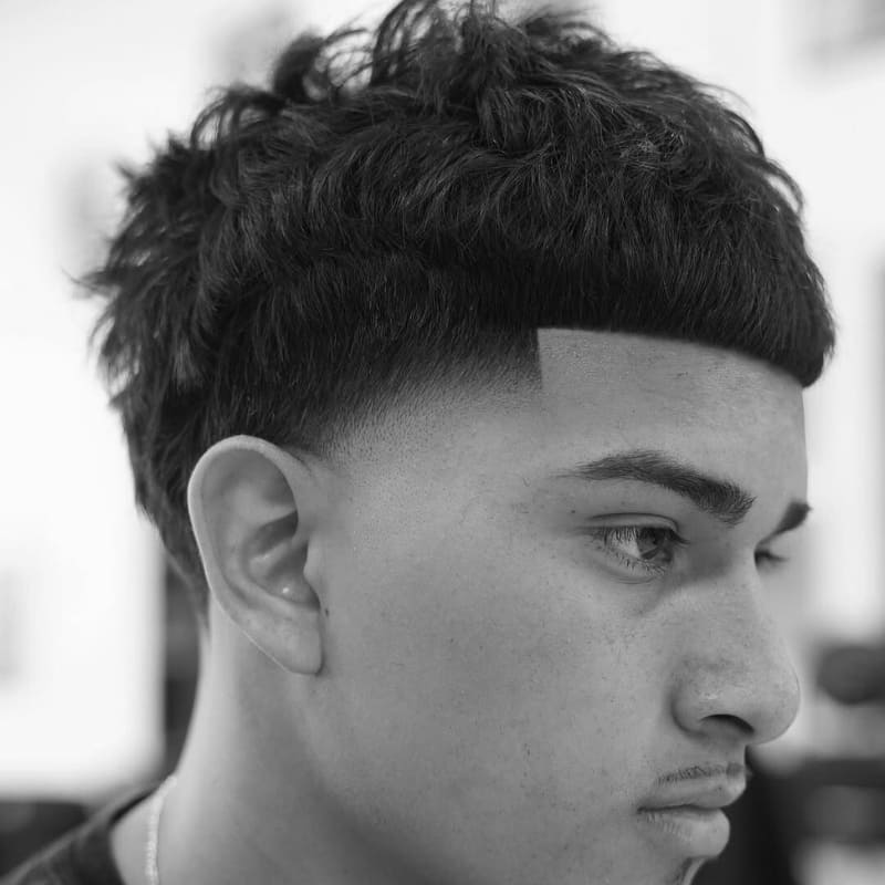 Man with a Edgar haircut featuring a blunt fringe and clean fade on the sides for a bold, contemporary look.