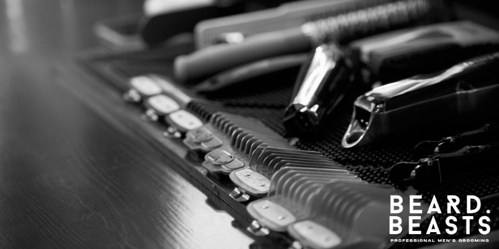 A black-and-white image showcasing professional hair clippers, guards, and grooming tools neatly arranged on a barbershop table. The variety of clipper guards, including the size needed for a number 4 buzz cut, emphasizes precision and versatility in achieving different hair lengths.