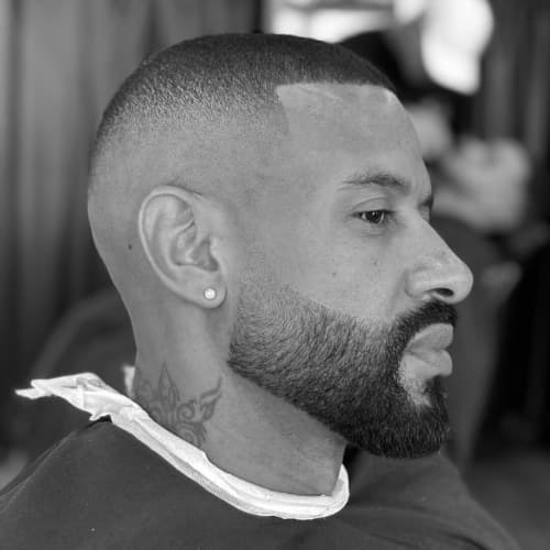 A sharp and stylish high fade haircut for Black men, featuring a seamless skin fade that blends into a short, textured top. The crisp lineup and well-groomed, full beard create a clean and polished look, making this fade haircut a bold yet sophisticated choice for men who want a fresh, modern style.