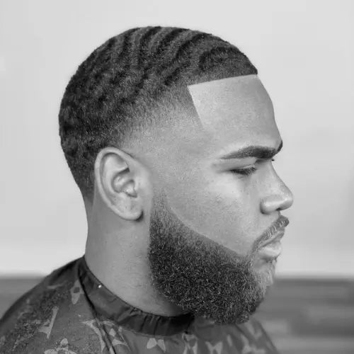 A sharp high taper fade haircut with 360 waves, featuring a precise skin fade that seamlessly blends into the well-defined waves on top. The crisp lineup and neatly shaped beard enhance the clean and polished look, making this fade haircut a stylish and modern choice for men who want a fresh and well-groomed appearance.