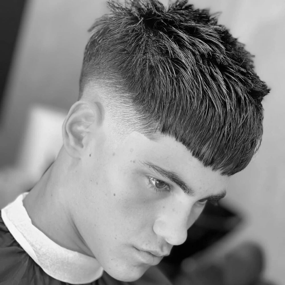 A man with a layered French crop with a skin fade, a clean and modern option for layered haircuts for men. The style has a textured fringe on top.