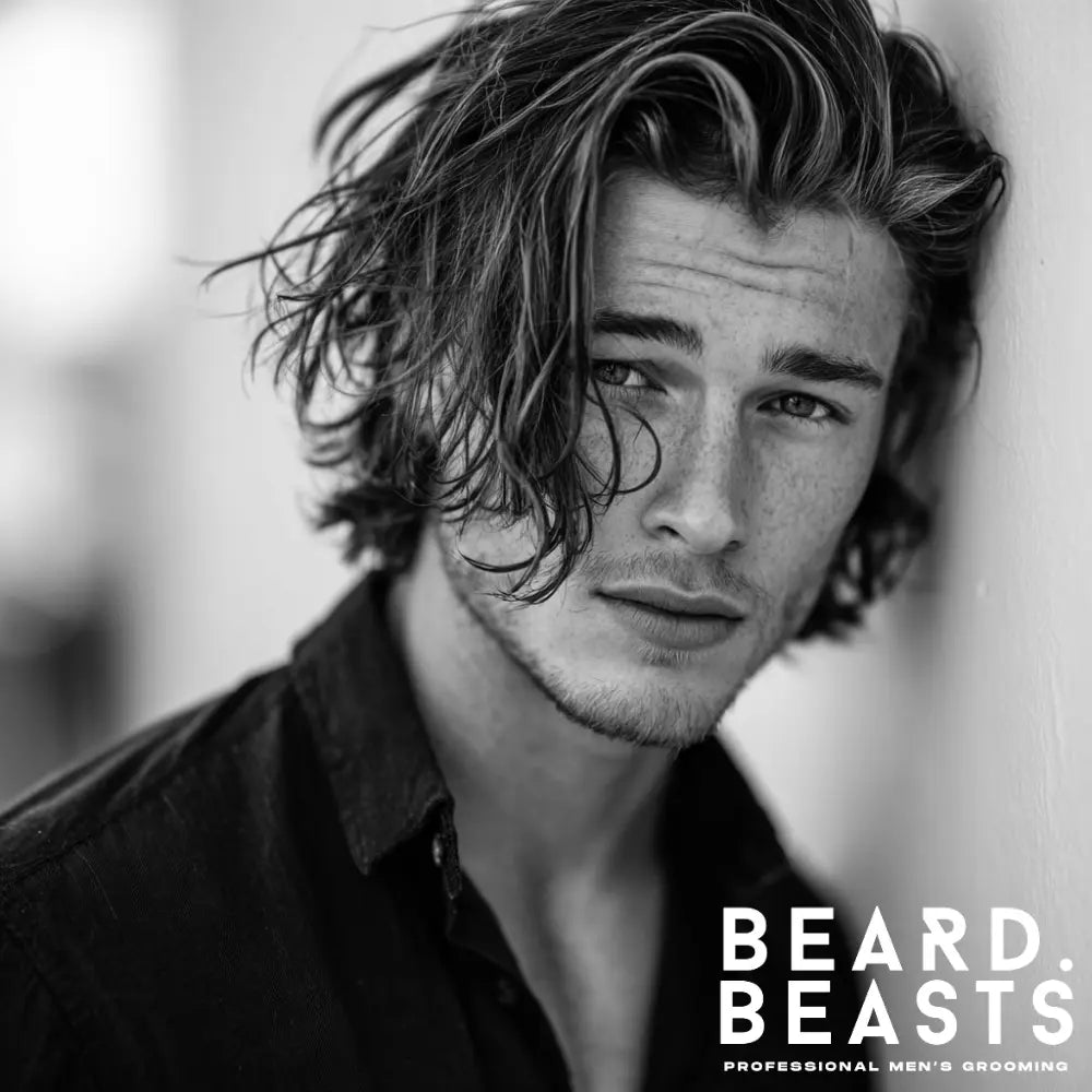 A man with a medium flow haircut, which is a popular example of layered haircuts for men. His wavy hair is natural and effortless.