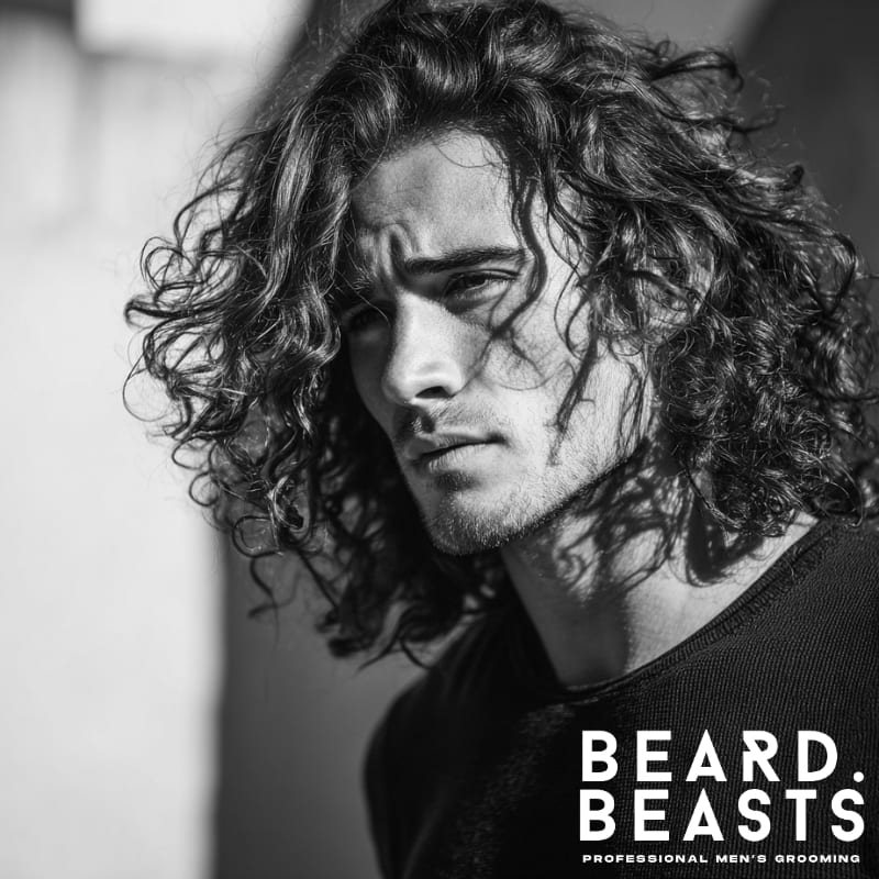 A modern men’s hairstyle featuring long, curly hair with natural volume and texture. This bold look combines effortless waves, ideal for men with curly hair who want a relaxed yet stylish appearance. A perfect example of men’s hairstyles for long hair that exude confidence and individuality.