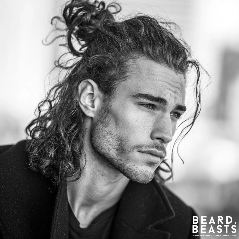 Long hairstyle for men with textured waves styled in a half-up look, combining casual flow with a controlled top knot.
