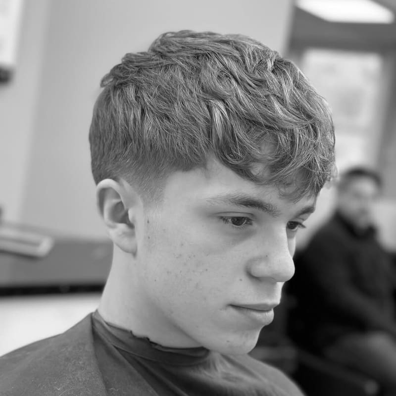 Young man with a textured crop and low fade, featuring soft layers on top and a low fade on the sides for a clean, stylish finish.